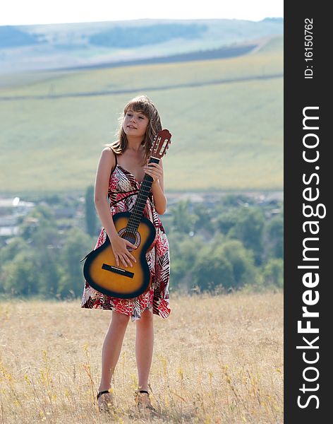 The young beautiful girl with a guitar in hands against open spaces. The young beautiful girl with a guitar in hands against open spaces.