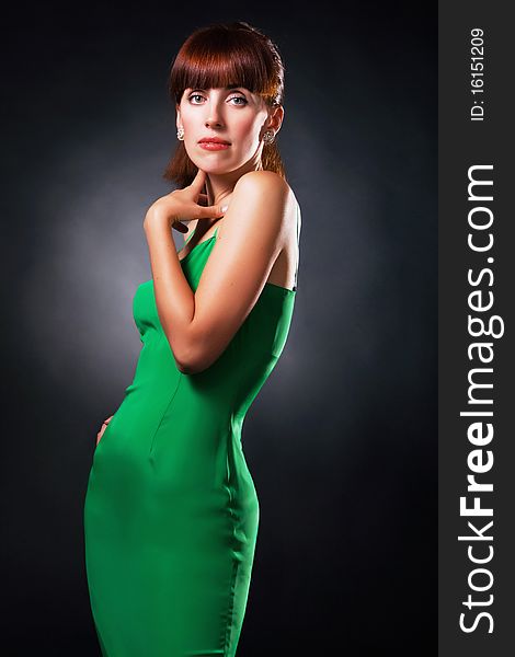 Beautiful elegant woman in green gown against black background