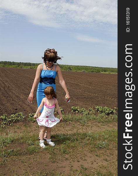 Mum with a small daughter against the ploughed field. Mum with a small daughter against the ploughed field.