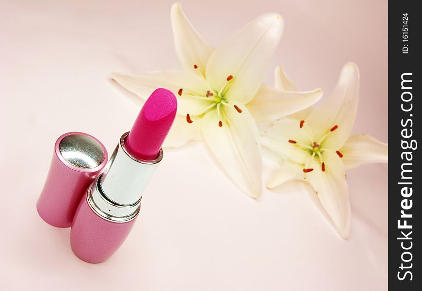 Red lipstick in pink box with lilies on background. Red lipstick in pink box with lilies on background