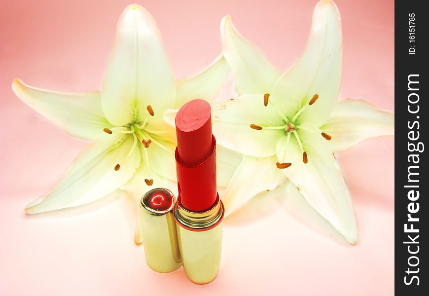 Red lipstick in gold box with lilies on background. Red lipstick in gold box with lilies on background