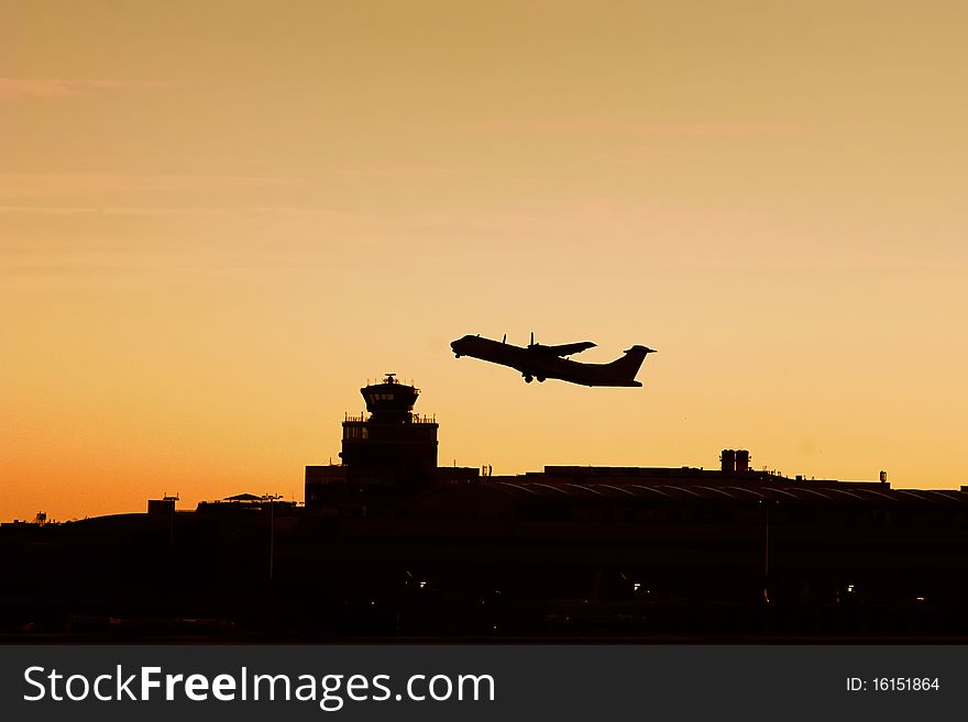 Turboprop plane flying over the airport tower in sunrise. Turboprop plane flying over the airport tower in sunrise