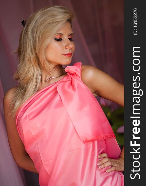 Beautiful sexy girl with blond hair and expressive eyes wearing in a pink dress. Beautiful sexy girl with blond hair and expressive eyes wearing in a pink dress