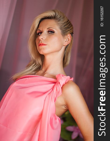 Beautiful sexy girl with blond hair and expressive eyes wearing in a pink dress. Beautiful sexy girl with blond hair and expressive eyes wearing in a pink dress