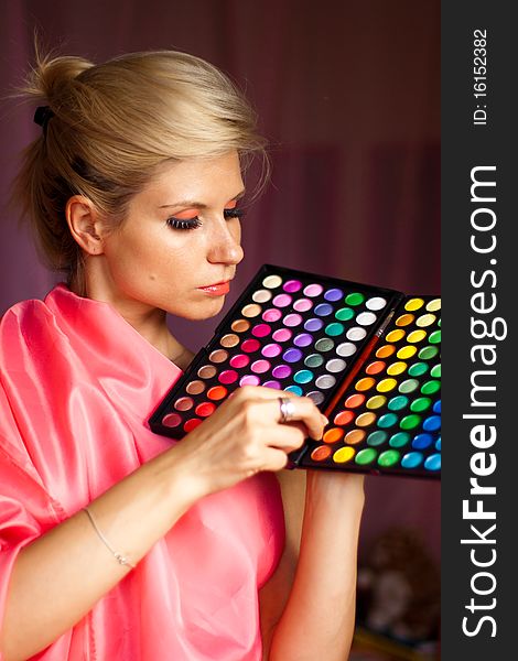 Beautiful girl holding a paintbrush and a box of colored eye shadow for make-up. Beautiful girl holding a paintbrush and a box of colored eye shadow for make-up