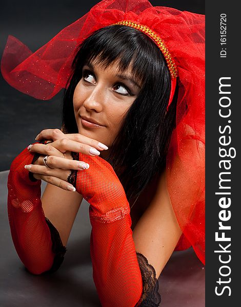 Beautiful dark-haired girl in a red wedding dress isolated on black background in studio. Beautiful dark-haired girl in a red wedding dress isolated on black background in studio