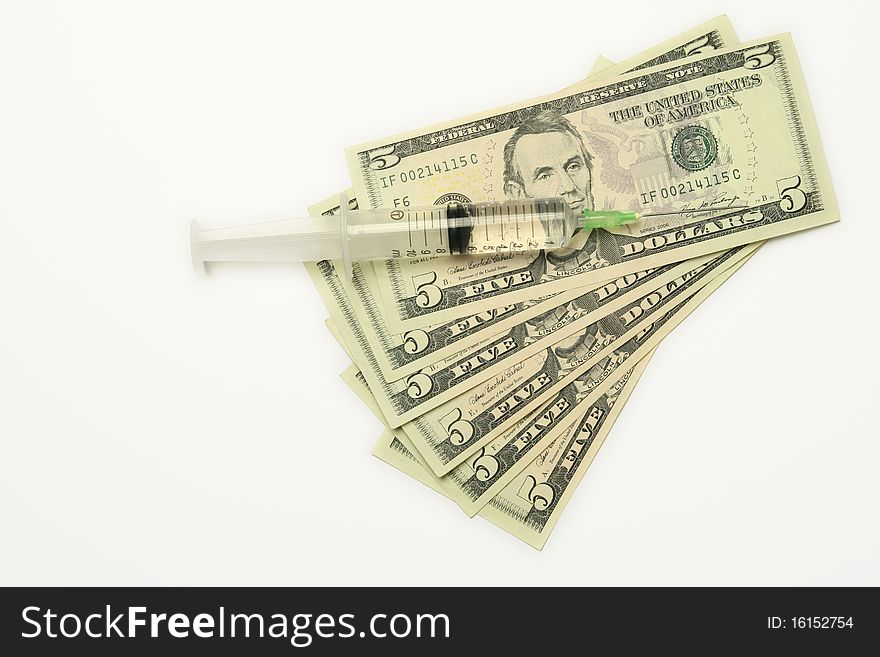 Five dollar bills and syringe isolated on white background