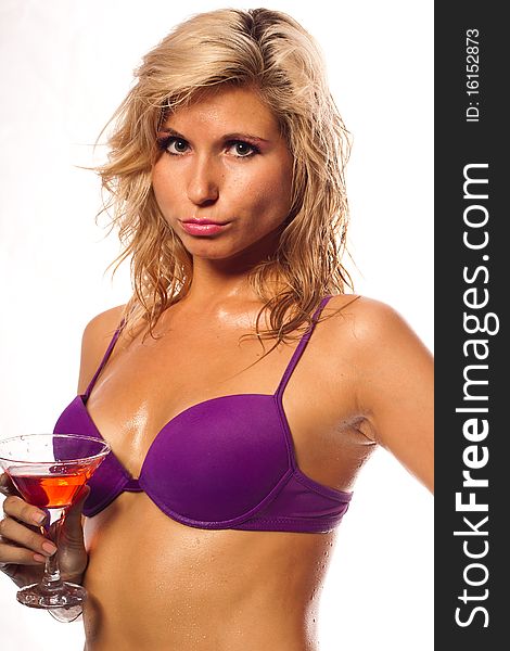 Beautiful girl in a wet violet bikini with glass of wine in the drops of water. She is in studio isolated on a white background. Beautiful girl in a wet violet bikini with glass of wine in the drops of water. She is in studio isolated on a white background