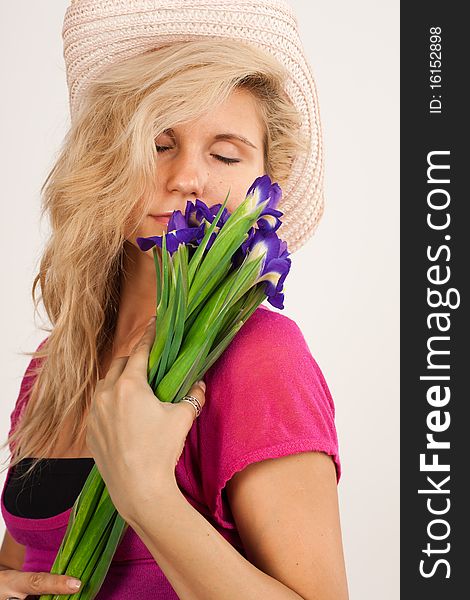 Beautiful girl with blonde hair holding a bouquet of irises. She is in studio isolated on a white background. Beautiful girl with blonde hair holding a bouquet of irises. She is in studio isolated on a white background