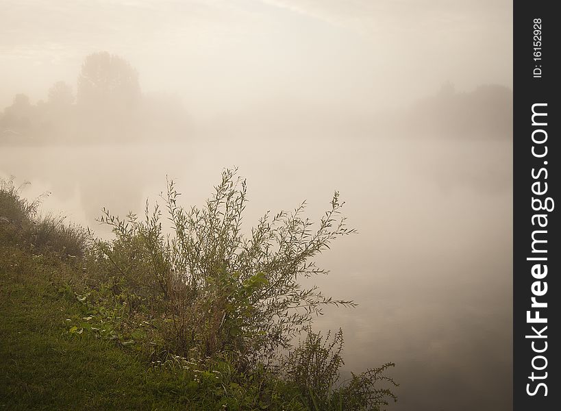 A misty early morning lake landscape with a calm water base. A misty early morning lake landscape with a calm water base