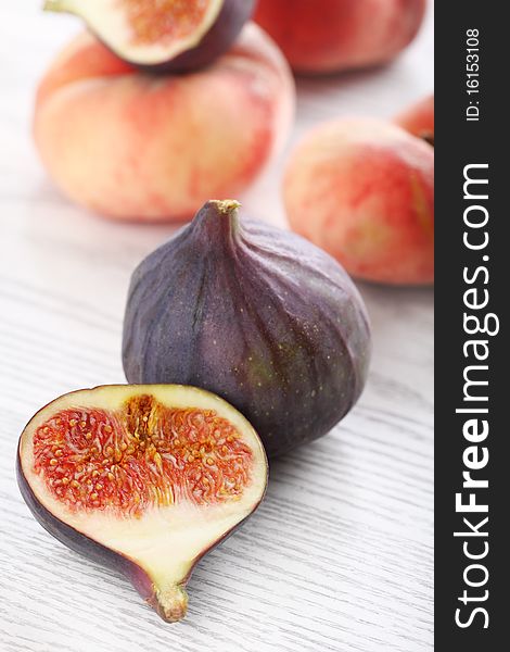 Fresh figs and peaches on the white wooden background