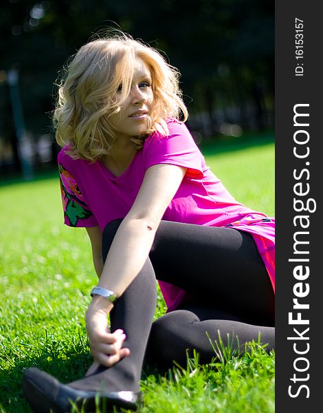 Young beautyful girl sitting on grass on a sunny day in a park. Young beautyful girl sitting on grass on a sunny day in a park