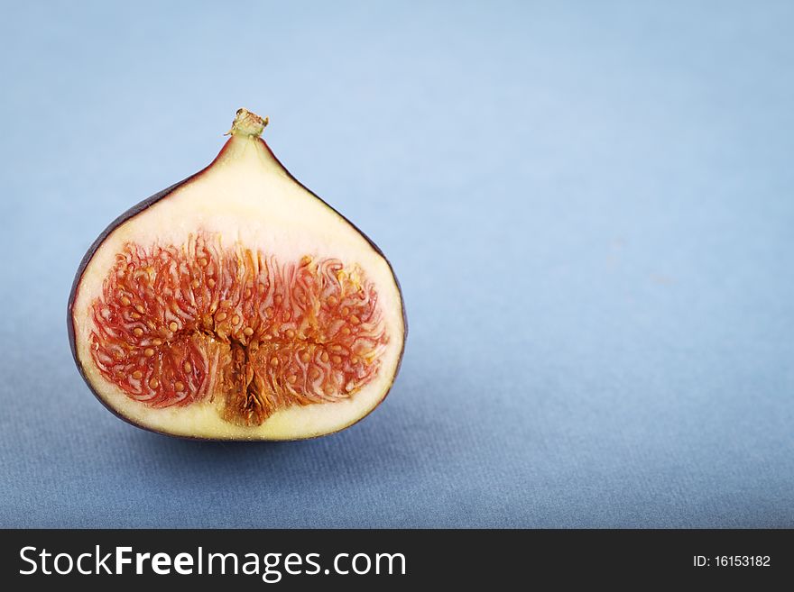 One halved fig on the blue background. One halved fig on the blue background