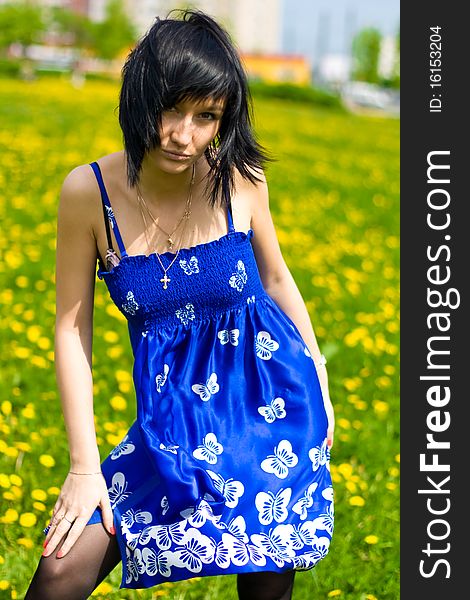 Summer girl in a blue dress against a background of green grass. Summer girl in a blue dress against a background of green grass