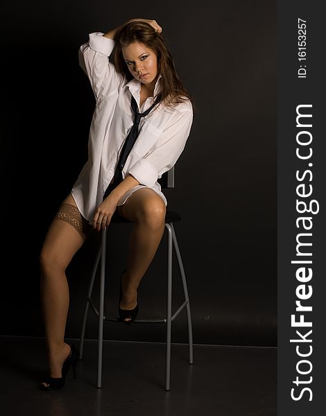 Young beautiful girl on a chair isolated on black background. Young beautiful girl on a chair isolated on black background