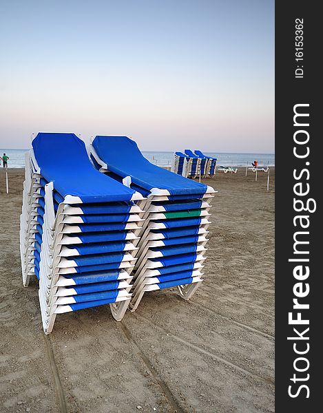 Stacked blue deckchairs on a beach