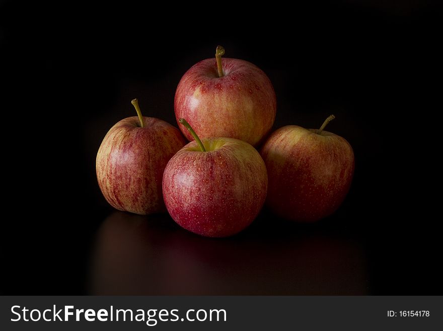 A group of four apples on a black background. A group of four apples on a black background.