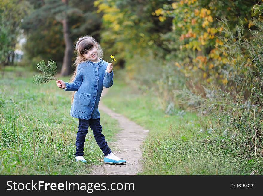 Adorable small girl with long dark hair in blue sweater the autumn forest. Adorable small girl with long dark hair in blue sweater the autumn forest