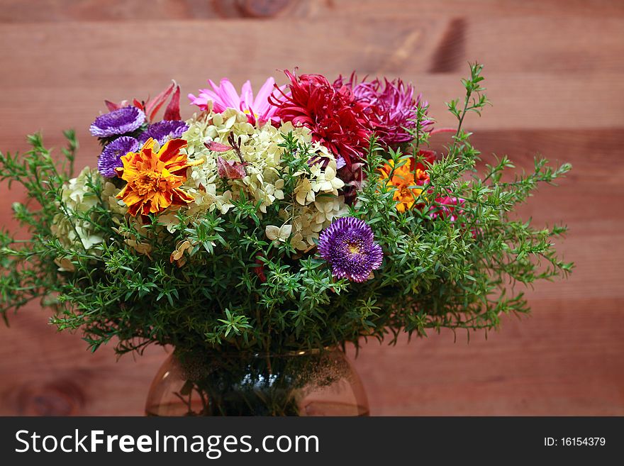 Glass vase with fresh flower bouquet on dark wooden background