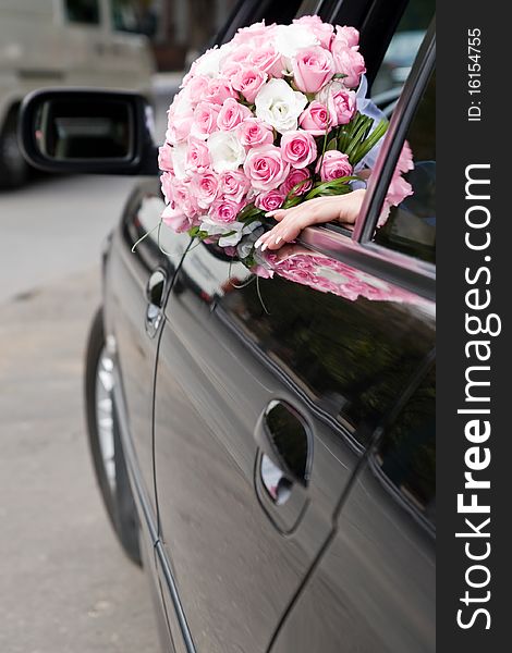 Hand of a bride sitting in a car with flowers. Hand of a bride sitting in a car with flowers