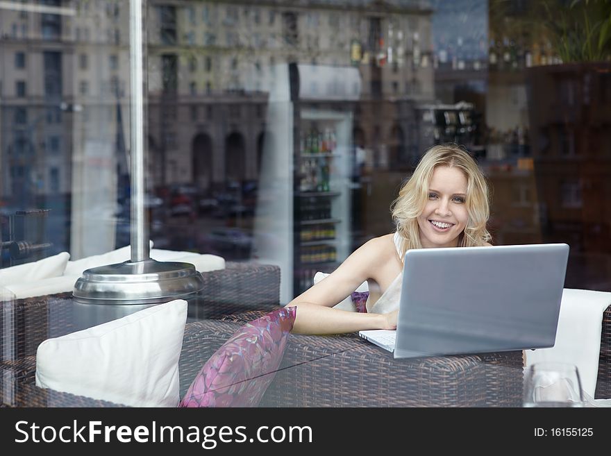 Happy young girl with laptop in restaurant. Happy young girl with laptop in restaurant