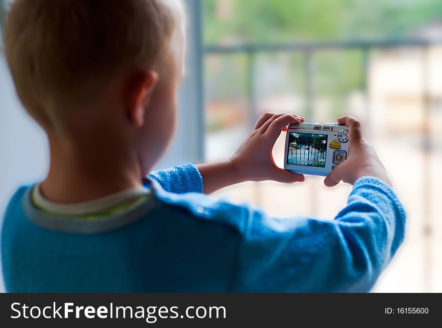 The child is photographing through a the window of his house. The child is photographing through a the window of his house