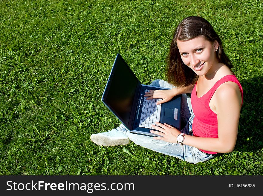 Pretty Brunette With A Laptop On A Green Lawn