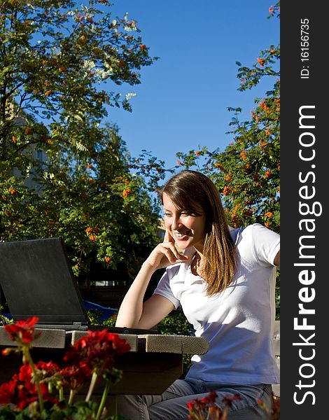 Young pretty woman with laptop sitting on the bench in a park. Young pretty woman with laptop sitting on the bench in a park