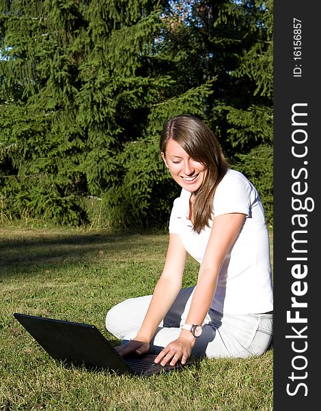 Smiling Girl With A Laptop On A Lawn