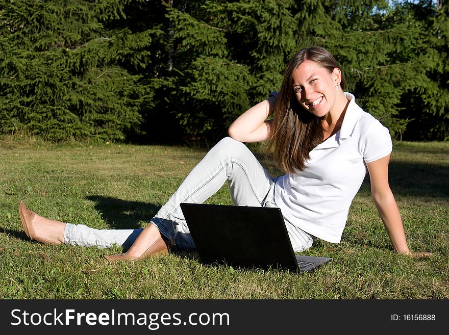 Smiling Girl With A Laptop On A Lawn