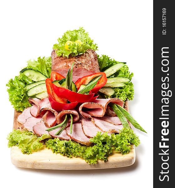 Whole Baked Ham on a cutting board decorated vegetables and herbs on white background