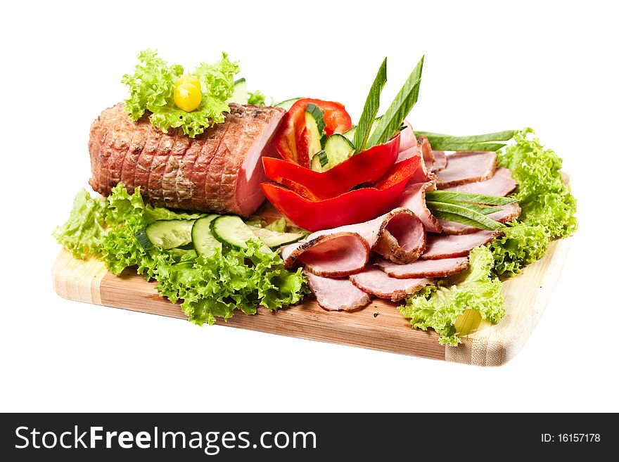 Whole Baked Ham on a cutting board decorated vegetables and herbs on white background