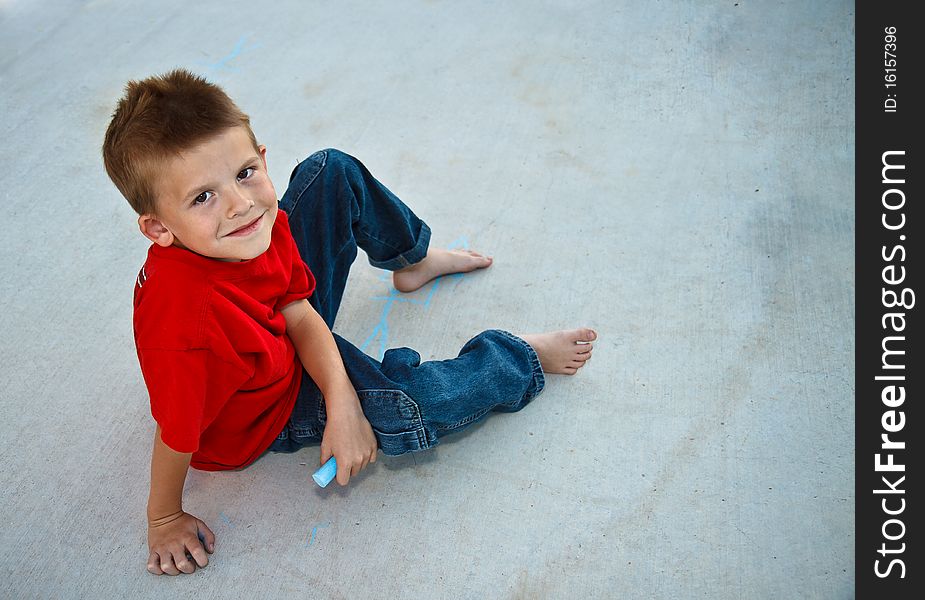 Cute young boy playing with sidewalk chalk