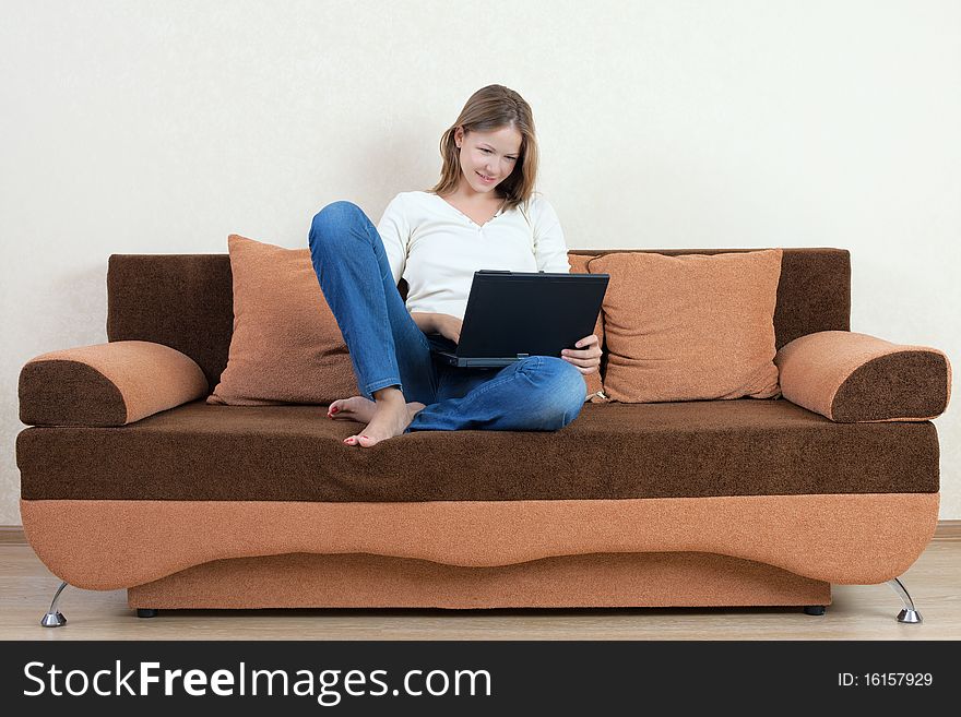 Young beatiful woman with laptop on the sofa