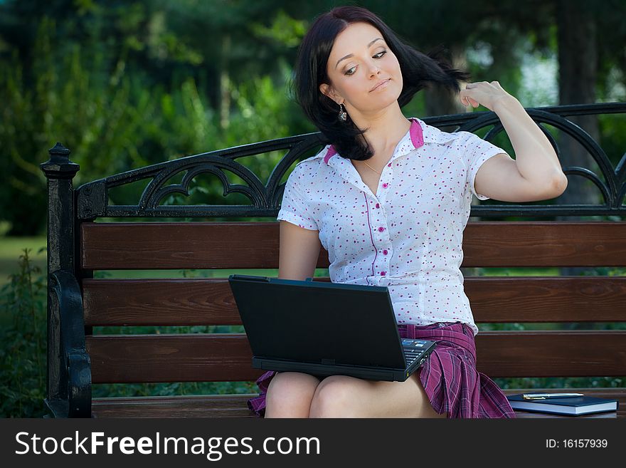 Young beautiful student girl with laptop in the park. Young beautiful student girl with laptop in the park