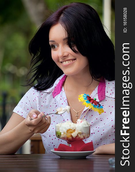 Young beautiful woman eating an ice cream in cafe. Young beautiful woman eating an ice cream in cafe