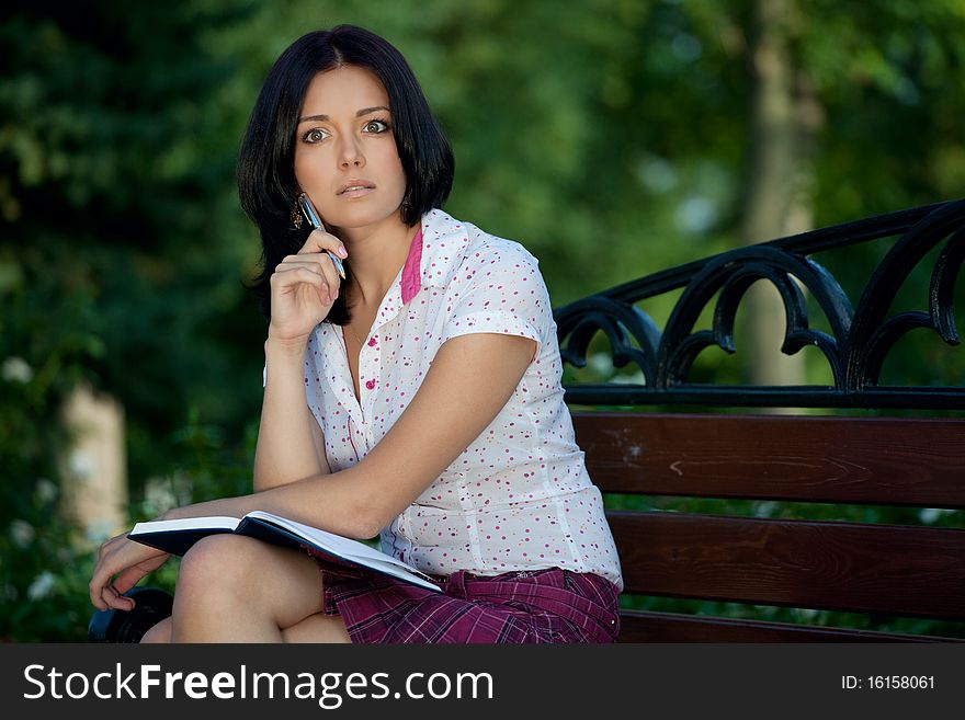 Young beautiful student girl with notepad in the park. Young beautiful student girl with notepad in the park