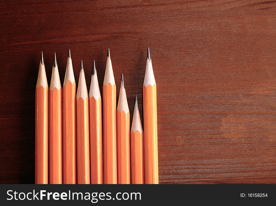 Few pencils standing in a row on dark wooden background with copy space