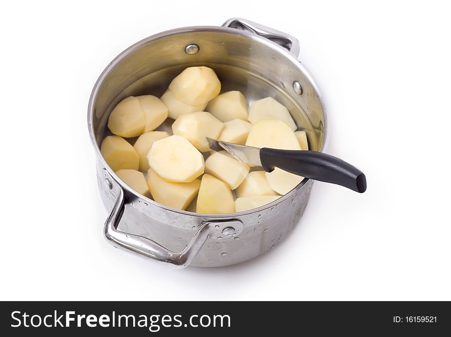 A pot with freshly peeled potatoes which still stuck the knife. The whole composition on white background. A pot with freshly peeled potatoes which still stuck the knife. The whole composition on white background.