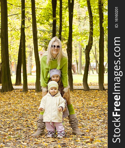 The woman with children costs nearby and smile in the autumn in park. The woman with children costs nearby and smile in the autumn in park