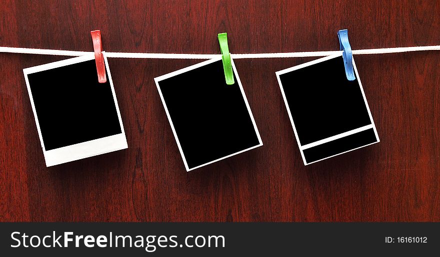 Frames attached to a rope on clothespins against a wooden background