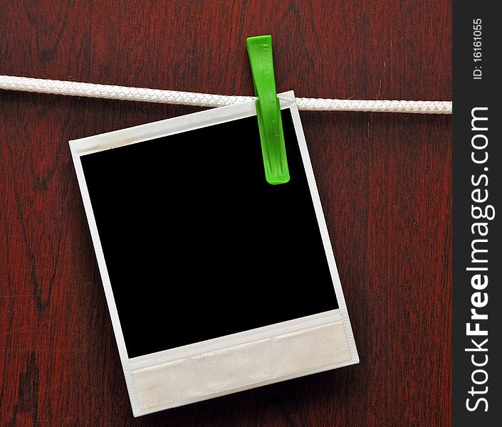 Frames attached to a rope on clothespins against a wooden background