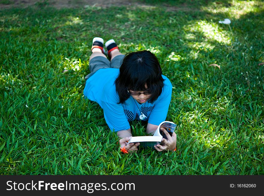 Little girl reading a book in the park.