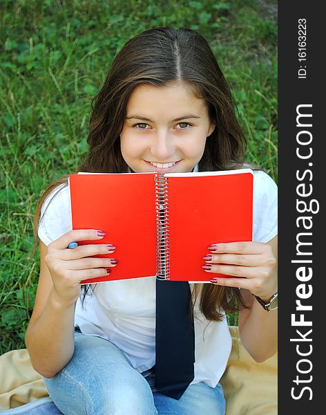 Beautiful young student girl is smiling and carrying red notebook. Beautiful young student girl is smiling and carrying red notebook