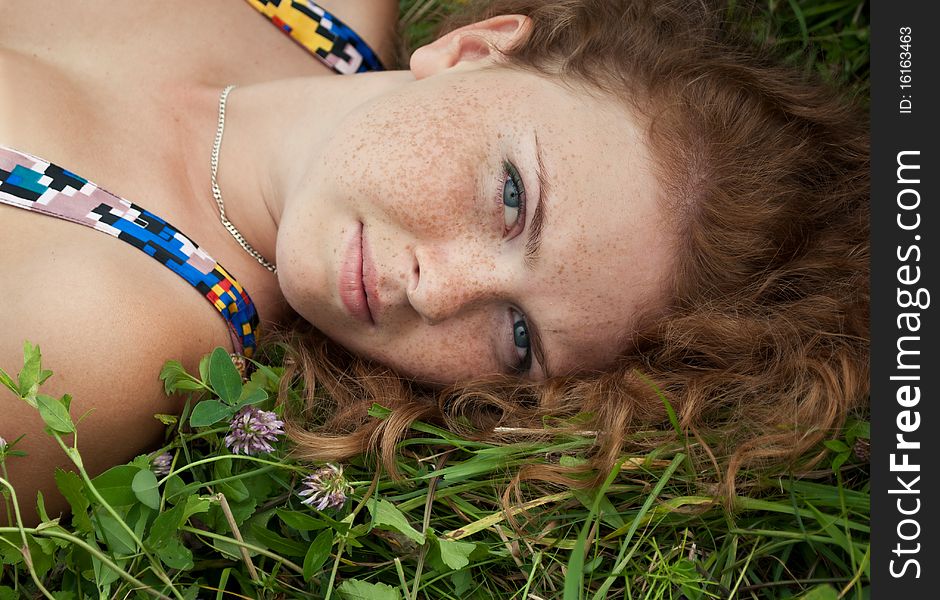 Beautiful ginger romantic girl is lying in the green grass. Beautiful ginger romantic girl is lying in the green grass