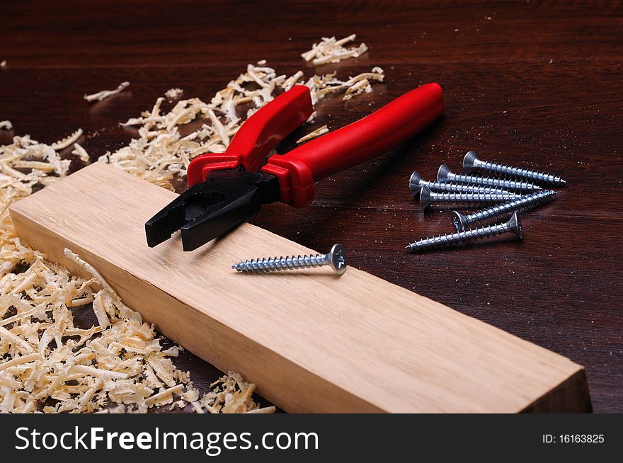 Shavings of wood, brick red and pliers on a dark background