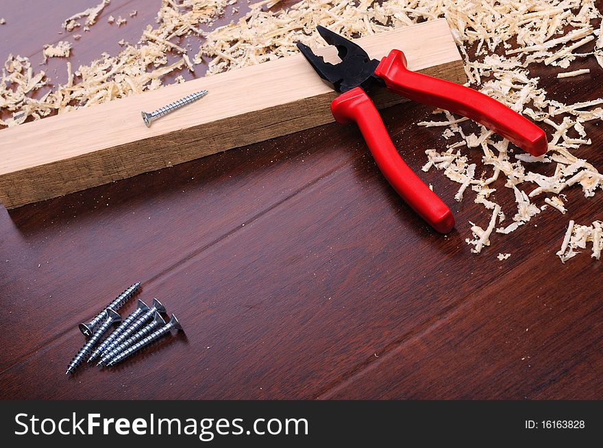 Shavings of wood, brick red and pliers on a dark background