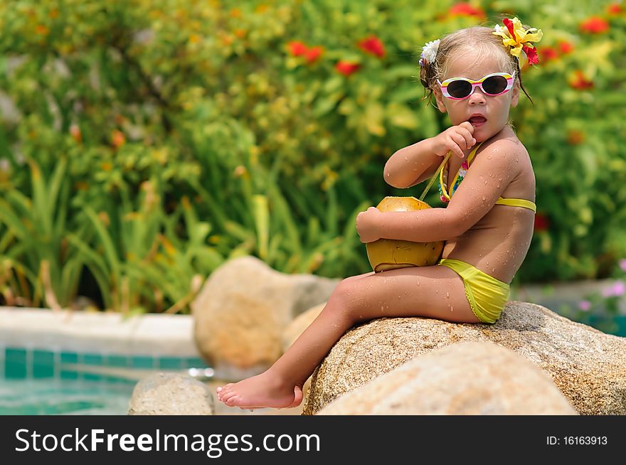 Portrait of cute toddler girl with coconut cocktail in the tropical beach