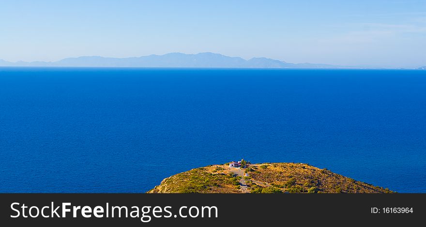 Cape, a lone house, the sea and the mountains in the distance. Rhodos. Greece