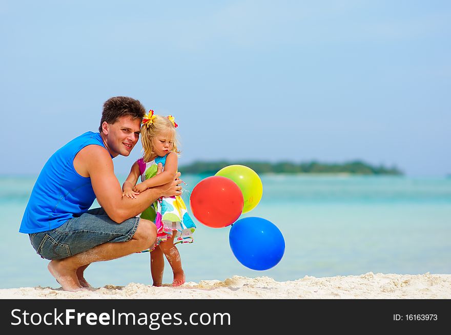 Young father and his cute daughter have a party with balloons on tropical beach. Young father and his cute daughter have a party with balloons on tropical beach